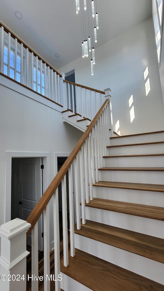 staircase with hardwood / wood-style floors and a high ceiling