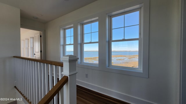 corridor with a water view and dark wood-type flooring