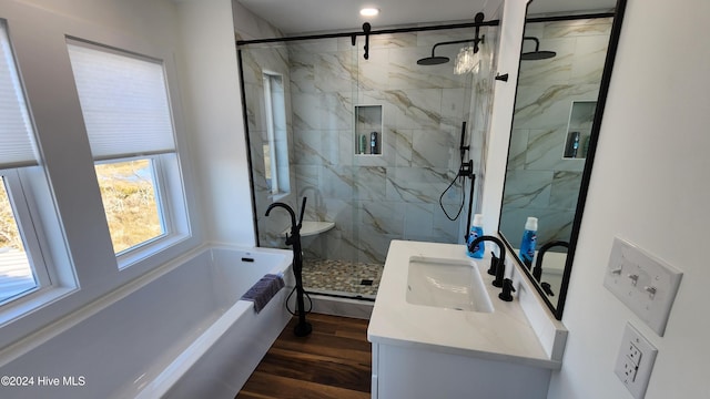 bathroom featuring plus walk in shower, vanity, and wood-type flooring