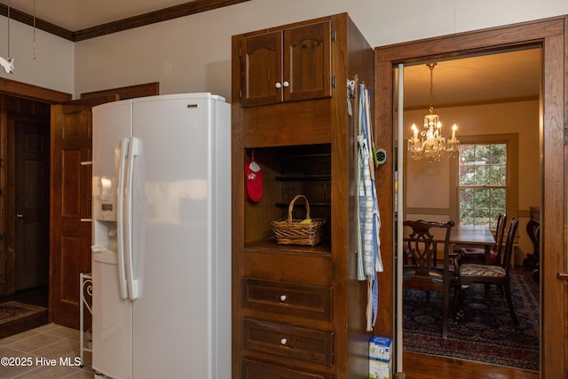 kitchen with decorative light fixtures, white fridge with ice dispenser, crown molding, and a chandelier