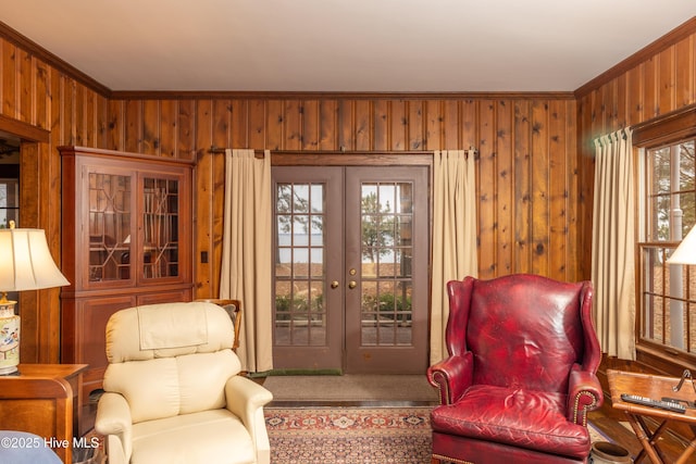 sitting room with wood walls, ornamental molding, and french doors