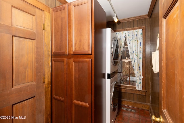 interior space with cabinets, wooden walls, and stacked washer and clothes dryer