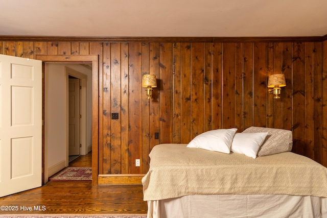 bedroom with wooden walls and wood-type flooring