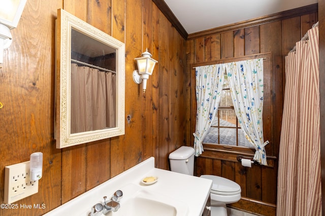 bathroom featuring toilet, ornamental molding, and wooden walls