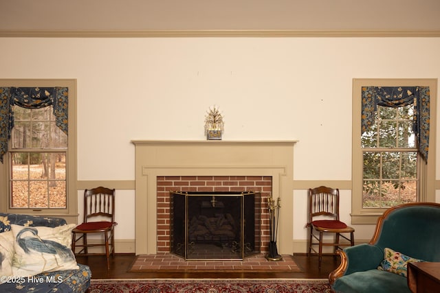 sitting room featuring a brick fireplace and crown molding