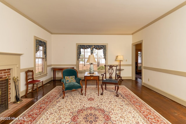 sitting room featuring dark wood-type flooring, ornamental molding, plenty of natural light, and a brick fireplace