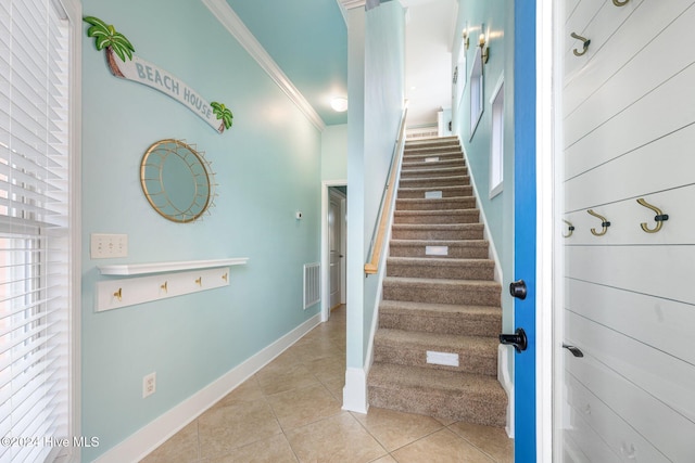 stairway with ornamental molding and tile patterned floors