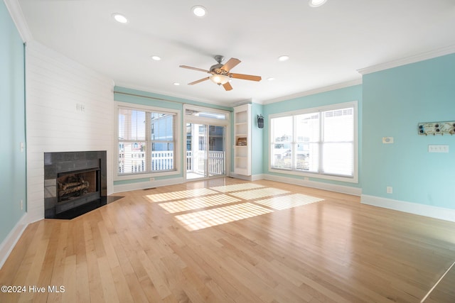 unfurnished living room featuring a fireplace, crown molding, light hardwood / wood-style flooring, and a healthy amount of sunlight