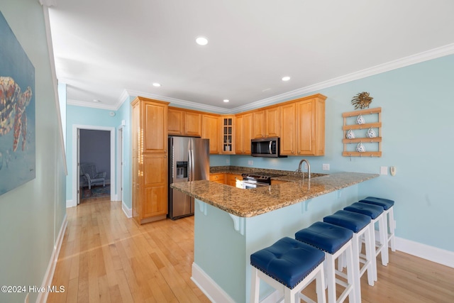 kitchen with stone counters, a kitchen bar, kitchen peninsula, stainless steel appliances, and light wood-type flooring