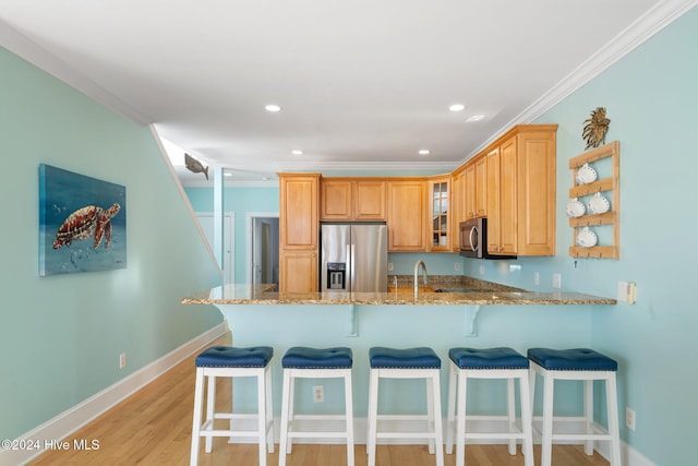 kitchen with crown molding, stainless steel appliances, light stone counters, light hardwood / wood-style floors, and kitchen peninsula