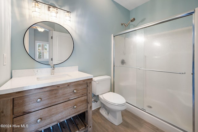 bathroom featuring vanity, hardwood / wood-style flooring, a shower with door, and toilet