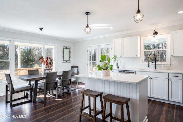 kitchen featuring white cabinets, decorative light fixtures, a kitchen island, and sink