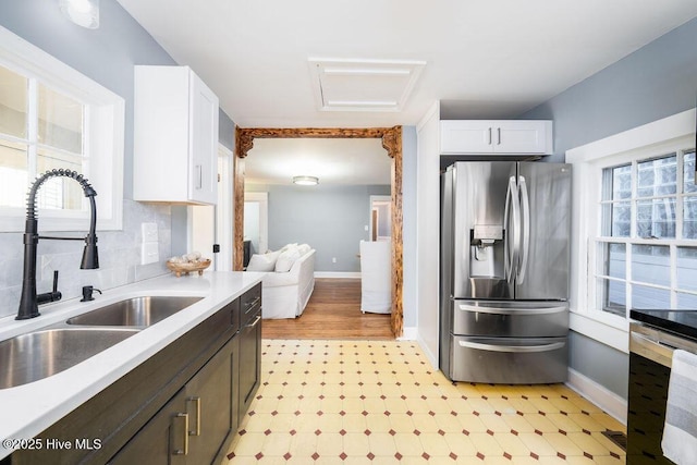 kitchen with white cabinets, stainless steel fridge, dark brown cabinets, and sink