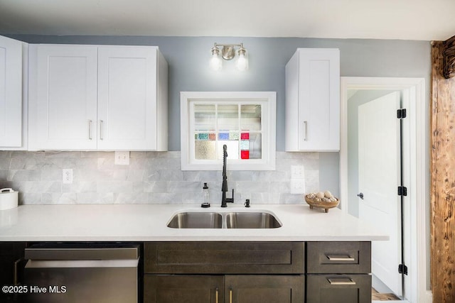 kitchen featuring tasteful backsplash, white cabinetry, sink, and stainless steel dishwasher