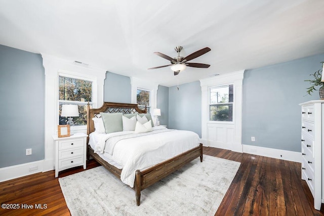 bedroom with ceiling fan, dark wood-type flooring, and multiple windows