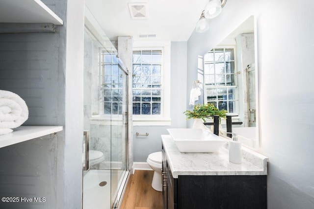 bathroom featuring hardwood / wood-style floors, vanity, toilet, and an enclosed shower