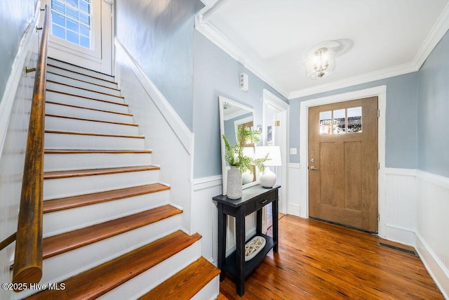 entryway with hardwood / wood-style floors, a notable chandelier, and ornamental molding