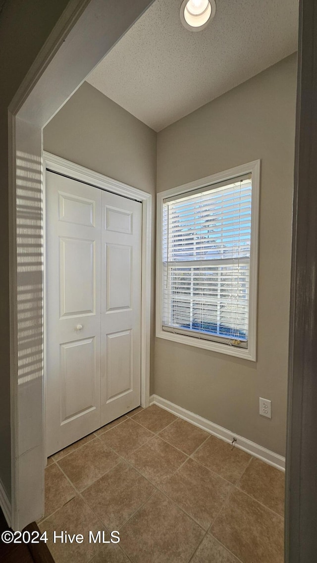 unfurnished bedroom with light tile patterned flooring, a textured ceiling, and a closet