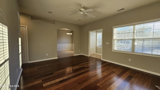 spare room featuring ceiling fan with notable chandelier and dark wood-type flooring