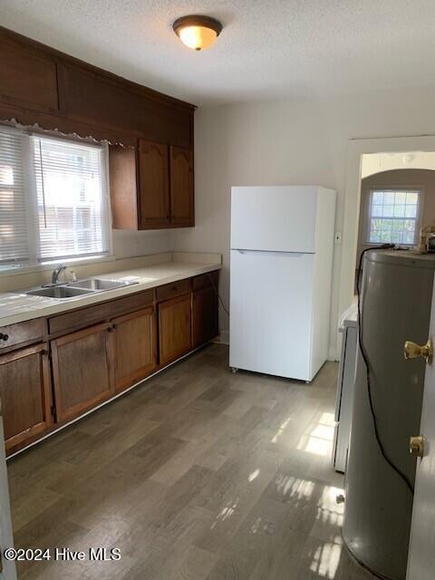 kitchen with a textured ceiling, white refrigerator, sink, and a wealth of natural light