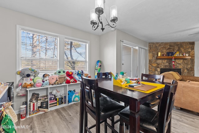 dining space with a fireplace, light hardwood / wood-style floors, and a notable chandelier