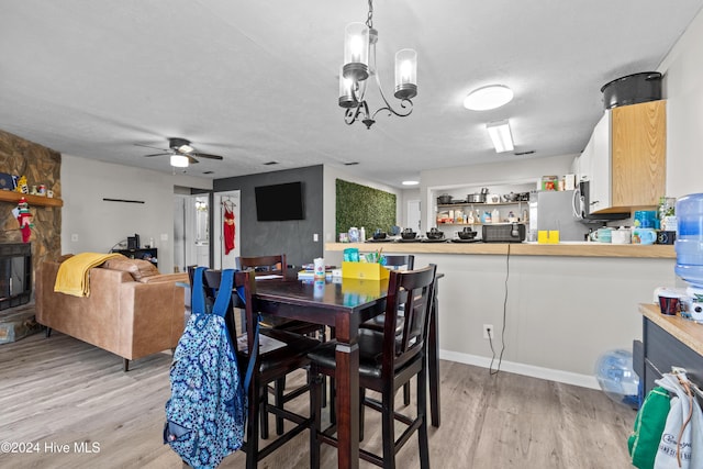 dining space with a textured ceiling, ceiling fan with notable chandelier, and light hardwood / wood-style flooring