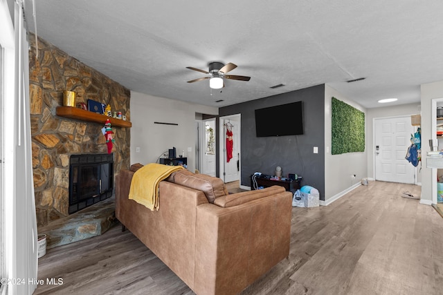 living room with a fireplace, a textured ceiling, hardwood / wood-style flooring, and ceiling fan