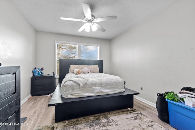 bedroom with ceiling fan, a textured ceiling, and light wood-type flooring