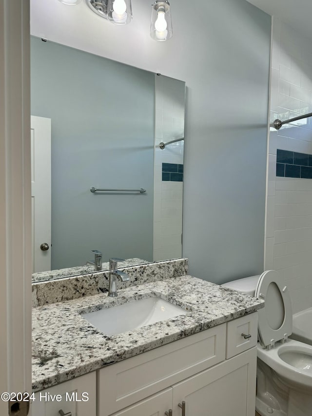 full bathroom featuring tiled shower / bath, vanity, and toilet