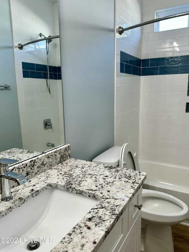 full bathroom with vanity, tiled shower / bath combo, and toilet