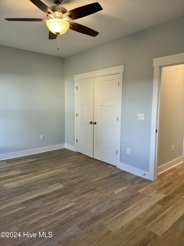 unfurnished bedroom featuring a closet, ceiling fan, and dark wood-type flooring