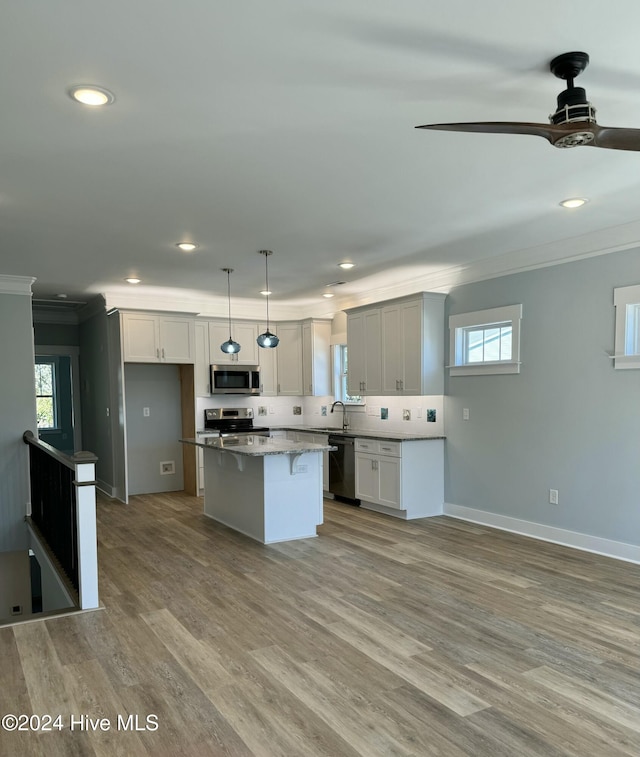 kitchen with a center island, hanging light fixtures, ceiling fan, appliances with stainless steel finishes, and white cabinetry