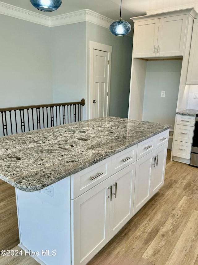 kitchen featuring light wood-type flooring, crown molding, decorative light fixtures, white cabinets, and a center island