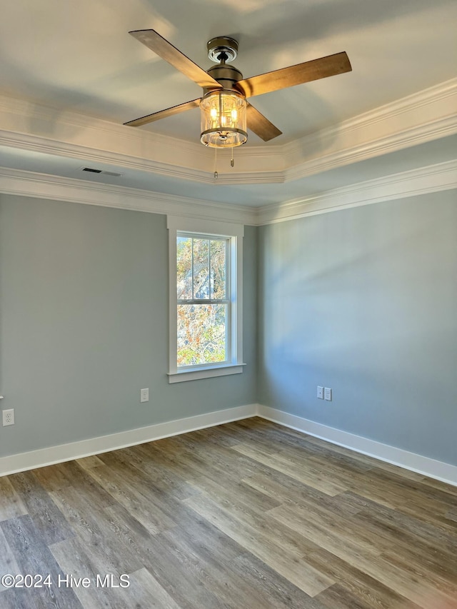 unfurnished room featuring wood-type flooring, a raised ceiling, ceiling fan, and crown molding