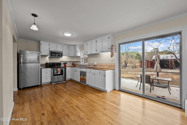 kitchen with white cabinetry, sink, stainless steel appliances, light hardwood / wood-style flooring, and pendant lighting