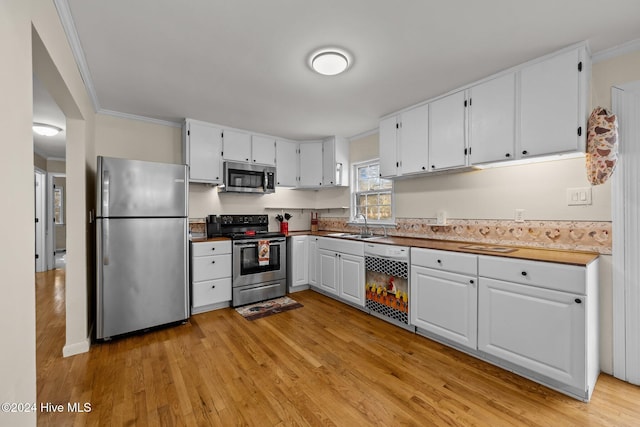 kitchen featuring stainless steel appliances, crown molding, sink, white cabinets, and light hardwood / wood-style floors