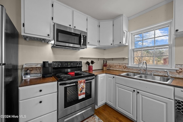 kitchen with hardwood / wood-style floors, white cabinets, crown molding, sink, and stainless steel appliances