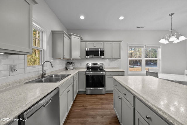 kitchen with backsplash, an inviting chandelier, sink, decorative light fixtures, and stainless steel appliances