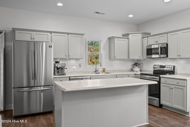 kitchen with gray cabinets, a kitchen island, sink, and appliances with stainless steel finishes