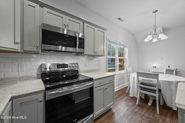 kitchen featuring stainless steel appliances, decorative light fixtures, a chandelier, gray cabinets, and lofted ceiling