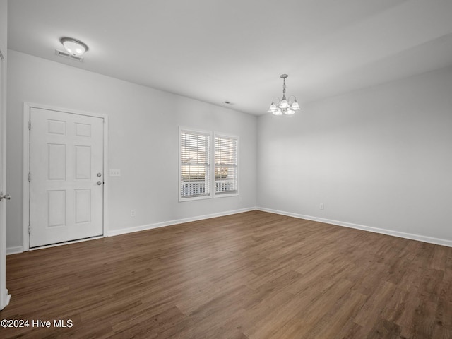 unfurnished room featuring dark wood-type flooring and a notable chandelier