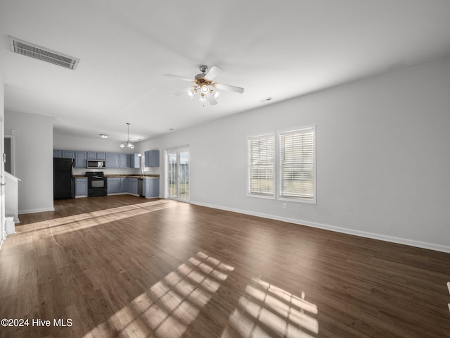 unfurnished living room with ceiling fan with notable chandelier and dark wood-type flooring