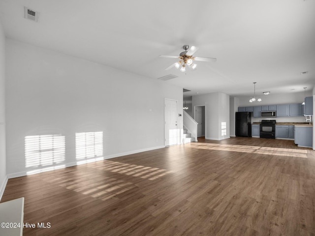 unfurnished living room with ceiling fan with notable chandelier and dark hardwood / wood-style flooring