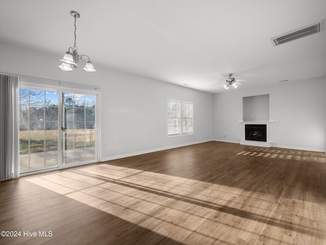 unfurnished living room with hardwood / wood-style flooring, ceiling fan with notable chandelier, and a healthy amount of sunlight