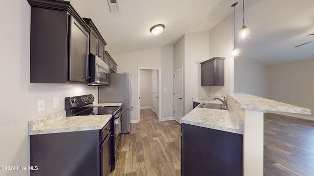 kitchen with kitchen peninsula, sink, electric range, decorative light fixtures, and a breakfast bar area