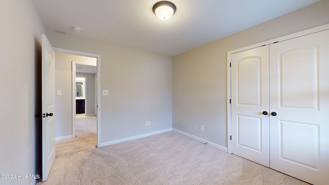 unfurnished bedroom featuring light colored carpet and a closet