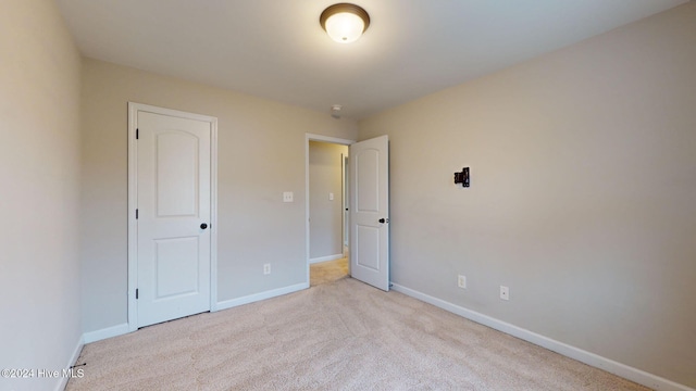 unfurnished bedroom with light carpet and a closet