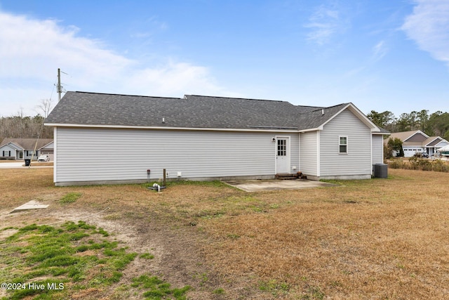 back of property with a lawn and central AC