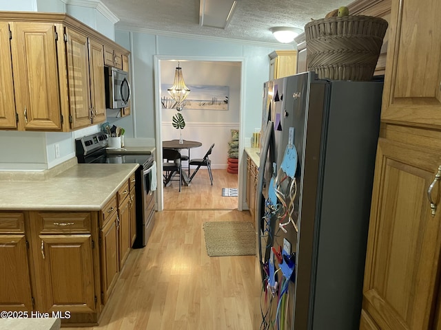 kitchen with a textured ceiling, light hardwood / wood-style floors, crown molding, and stainless steel appliances