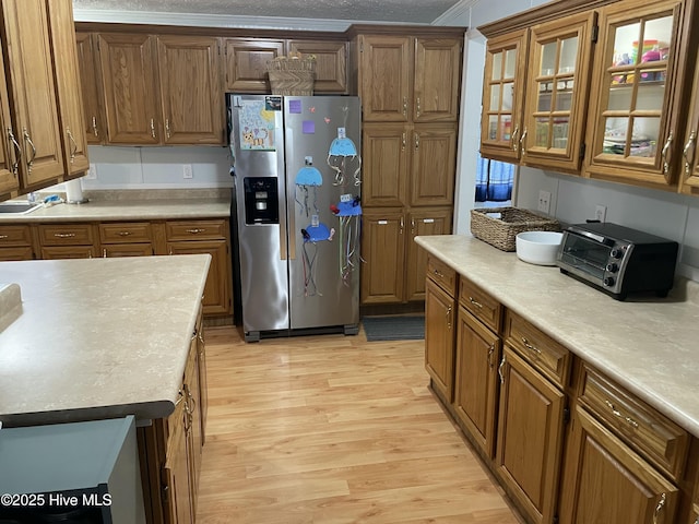 kitchen featuring stainless steel fridge, light wood-type flooring, ornamental molding, and a textured ceiling